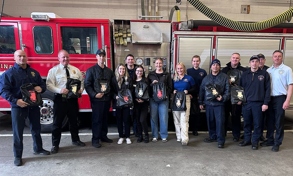 Members of the West Springfield Fire Department and ǿ޴ý OTD students pose for a photo with BEary Bags in front of a fire engine at the WSFD station.